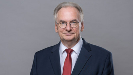 Foto von Rainer Haseloff. Er blickt ernst und trägt zu scharzem Jacket und weißem Hemd eine rote Krawatte.