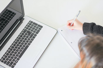 Frau vor dem Laptop macht sich Notizen