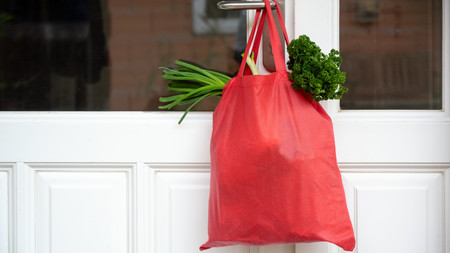 Einkaufstasche mit Lebensmitteln hängt an einer Türklinke
