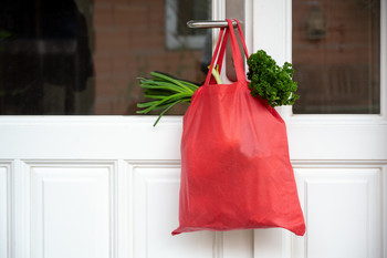 Einkaufstasche mit Lebensmitteln hängt an einer Türklinke