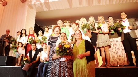 Petra Grimm-Benne und Susi Möbbeck mit dein Preistragenden auf und vor der Bühne verteilt