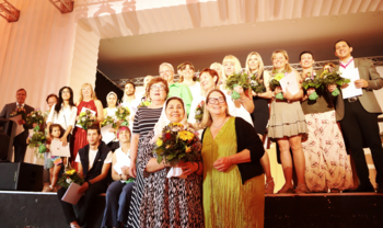 Petra Grimm-Benne und Susi Möbbeck mit dein Preistragenden auf und vor der Bühne verteilt