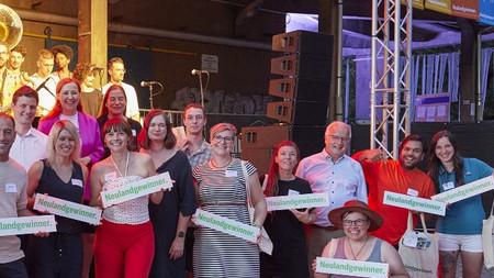 Menschengruppe mit Schildern in den Händen, auf denen "Neulandgewinner." steht