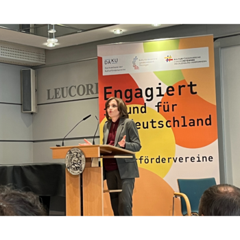 Elisabeth Kaiser, Ostbeauftragte der Bundesregierung, steht an einem Rednerpult und hält eine Rede am Tag der Kulturfördervereine in Wittenberg. Sie trägt einen grauen Hosenanzug und eine dunkle Bluse. Hinter ihr befindet sich ein großes Banner mit der Aufschrift „Engagiert für Deutschland“ und Logos des Dachverbands der Kulturfördervereine (DAKU) sowie weiterer Veranstalter.