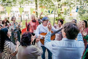 singende und tanzende Menschen, eine Person spielt Gitarre