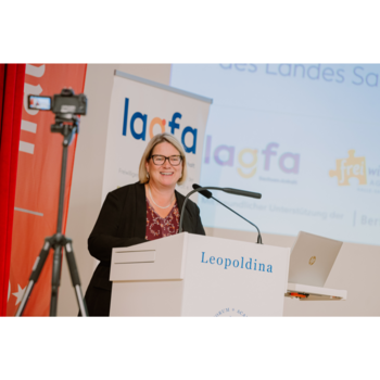 Integrationsbeauftragte Susi Möbbeck während ihrer Rede auf der Landeskonferenz; sie steht an einem Rednerpult, hinter ihr ist das Logo der lagfa zu sehen.