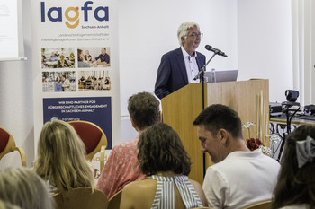 Staatsekretär Wolfgang Beck am Rednerpult, hinter ihm ein Aufsteller mit dem Logo der LAGFA Sachsen-Anhalt, vor ihm sitzendes Publikum