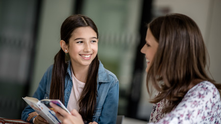 Lesementorin liest gemeinsam mit einer Schülerin ein Buch