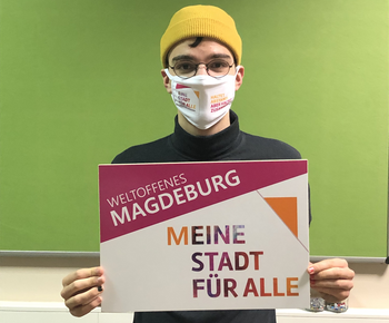 Engagierter mit Mund-Nasen-Schutz und Plakat zur Aktionswoche