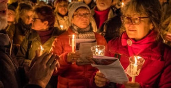 Gruppe Menschen, singend, mit Kerzen in den Händen