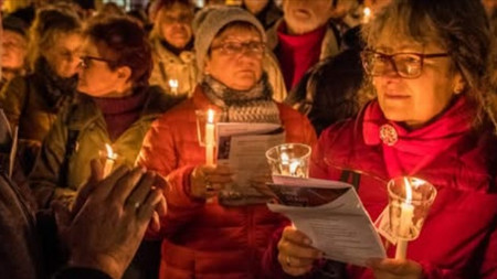 Gruppe Menschen, singend, mit Kerzen in den Händen