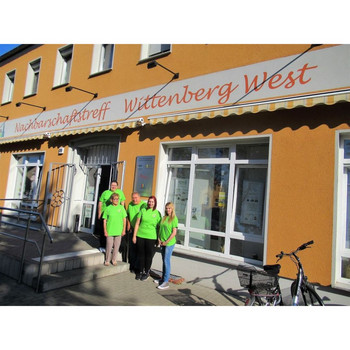 Fünf weiße Erwachsene in den gleichen neongrünen T-Shirts vor dem Eingang des Nachbarschaftstreffs Wittenberg West